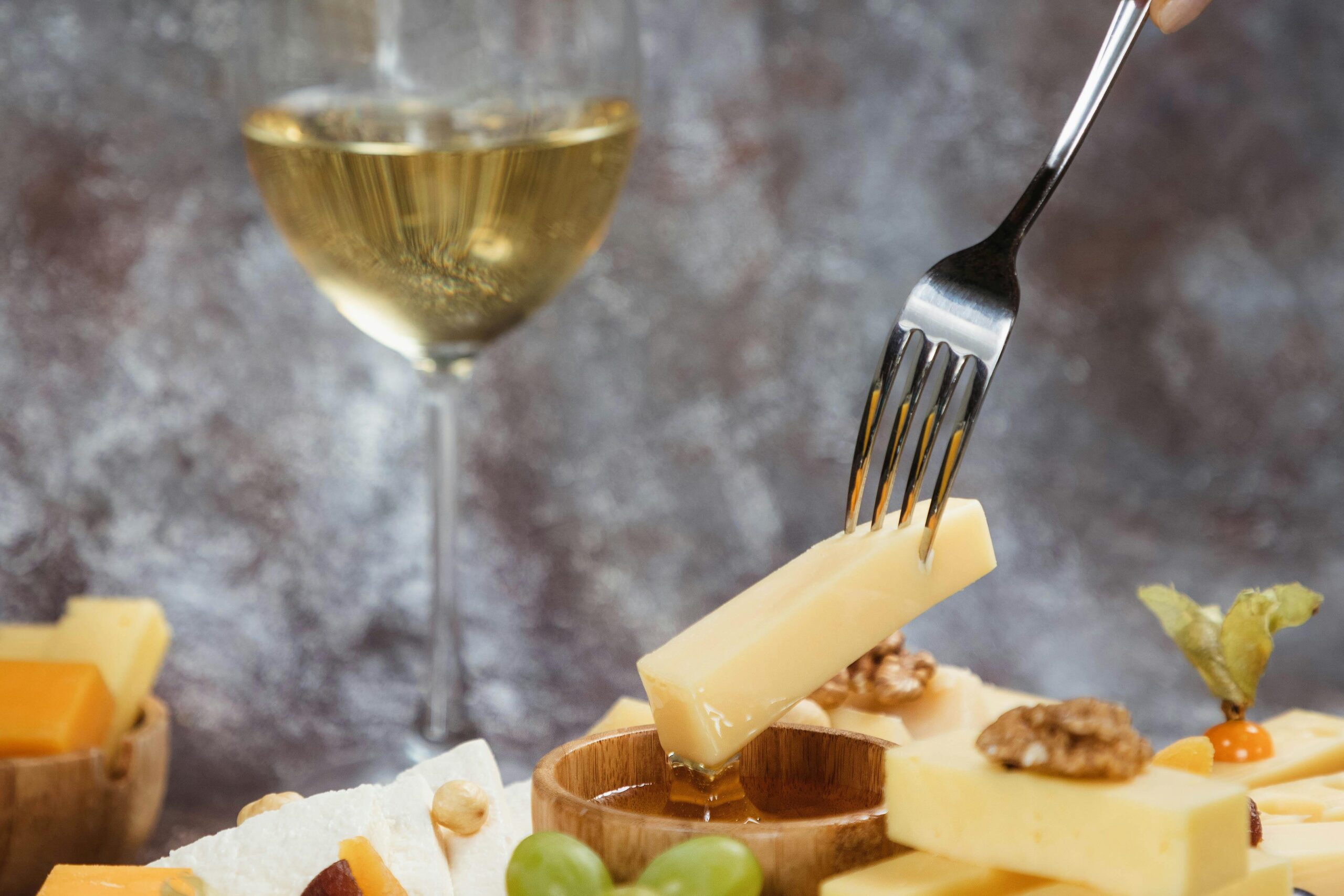 white wine next to a spread of cheese, grapes, and walnuts. 