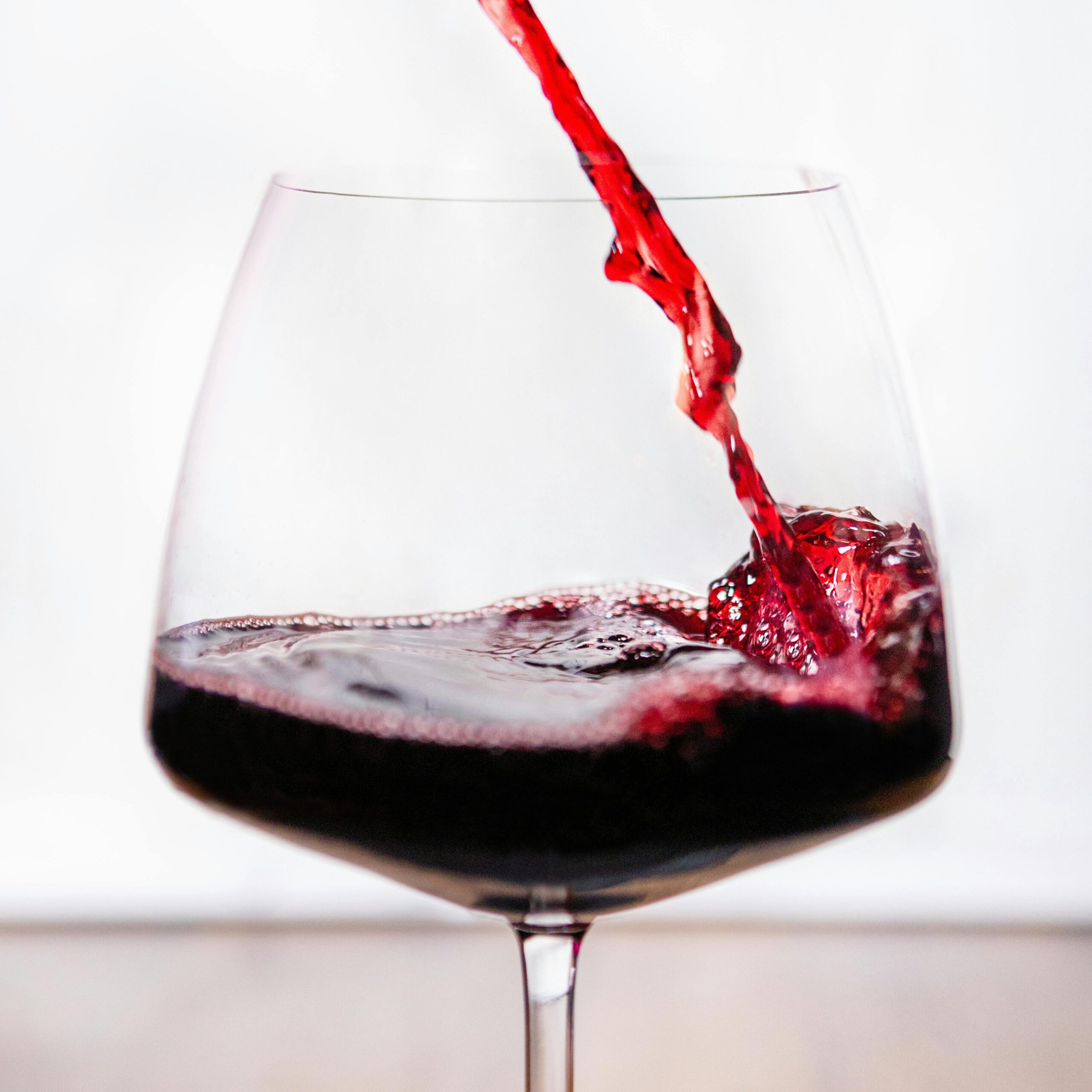 a red wine glass with red wine being poured into it