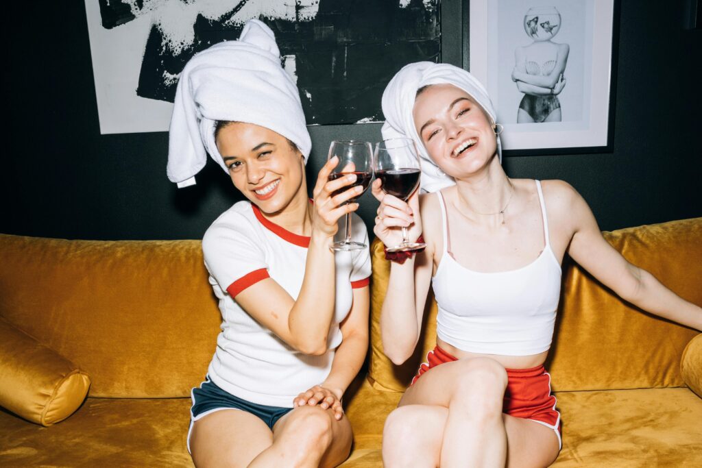 women clinking wine glasses sitting on the couch