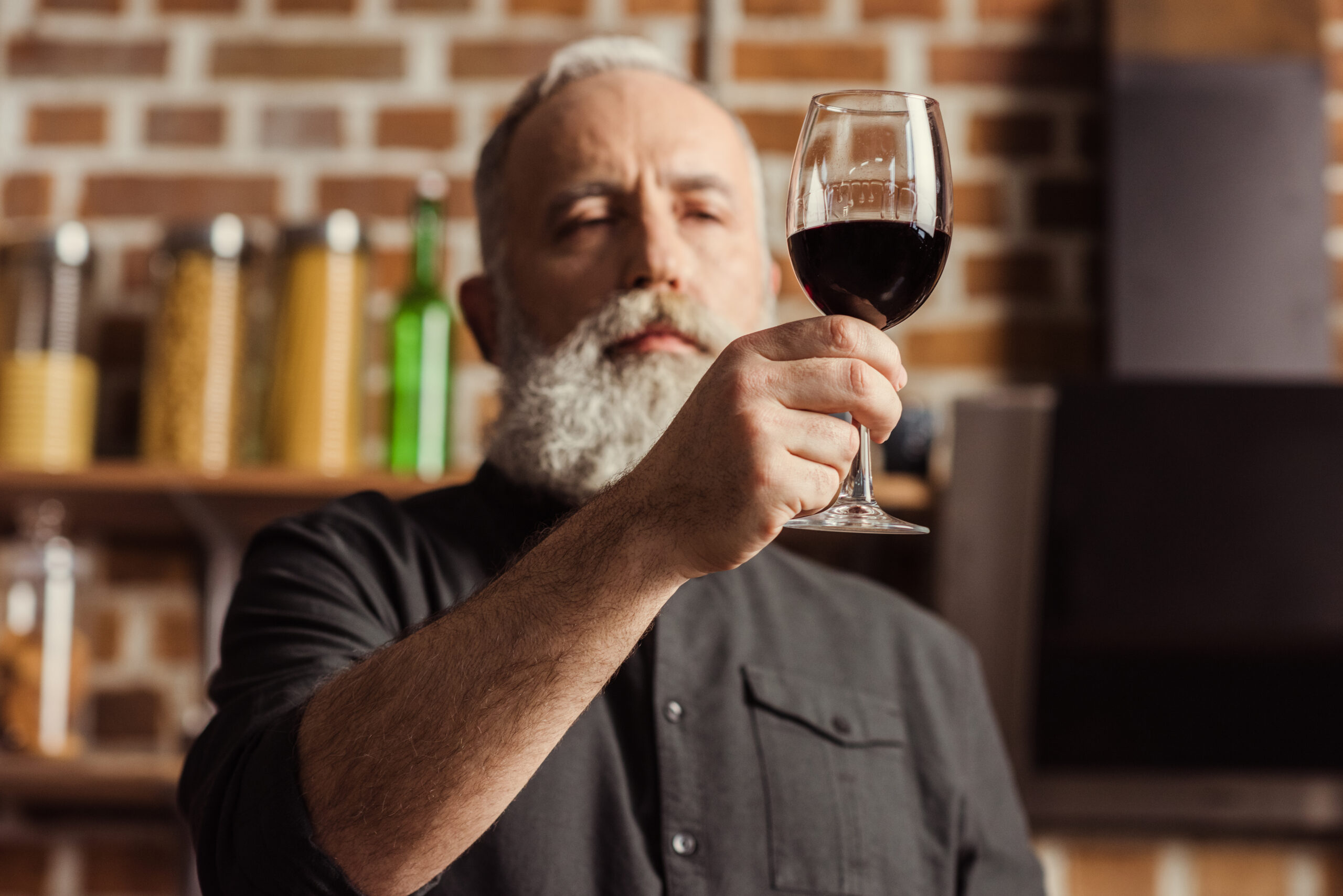 Sommelier examining the color of a glass of wine at a tasting event.