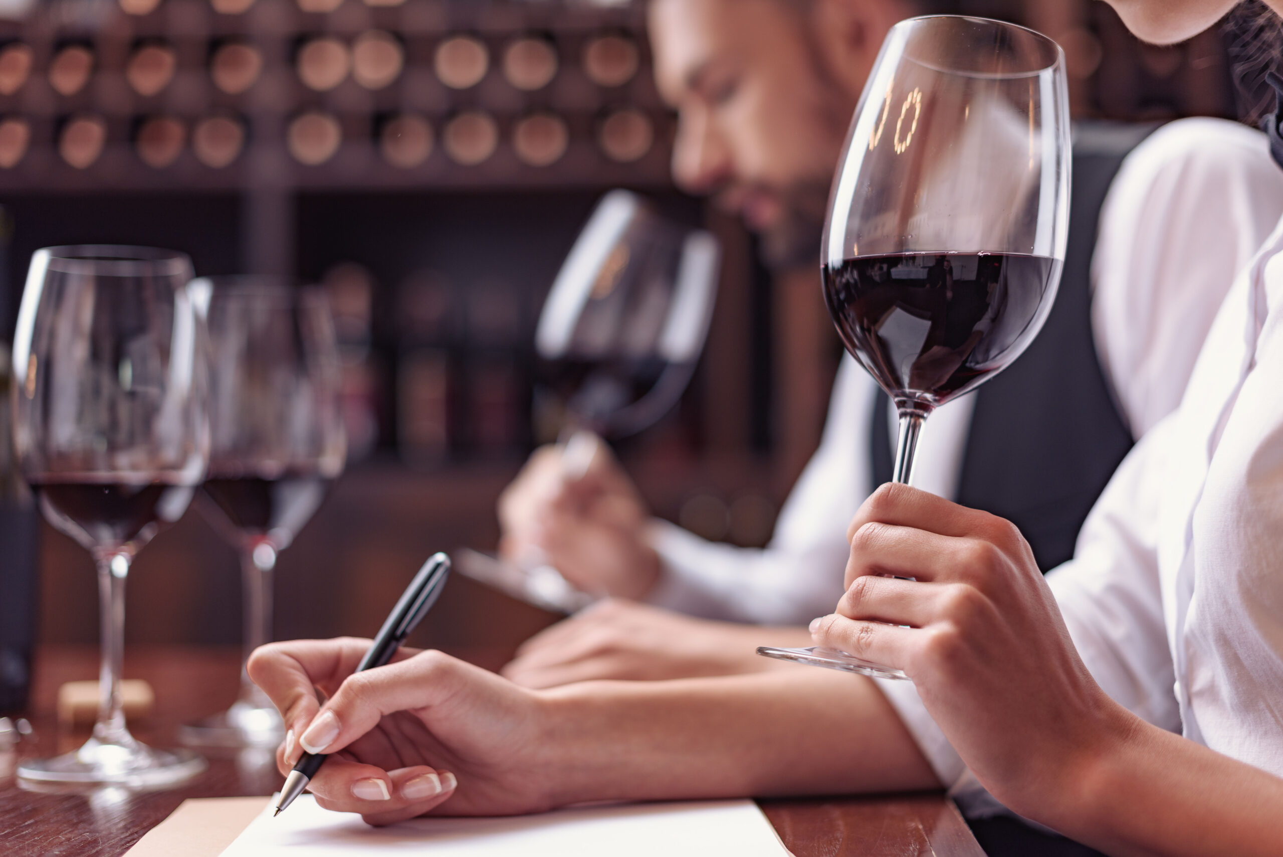 Sommelier taking notes on the characteristics of a wine during a professional tasting session.