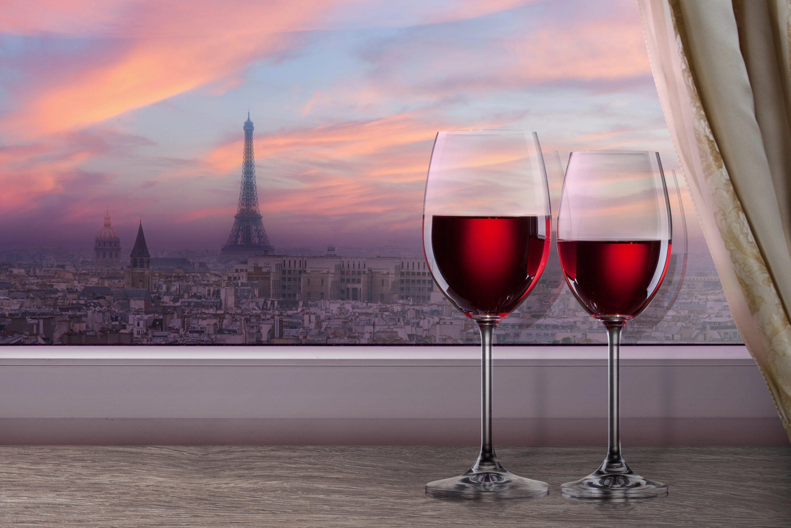 two glasses of red wine in a room overlooking the eiffel tower